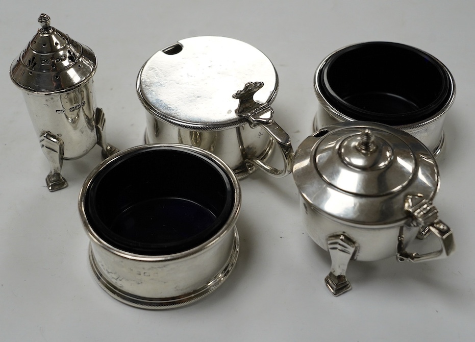 A George V matched silver three piece condiment set, London, 1931(2) and 1933, together with two other silver condiments. Condition - poor to fair